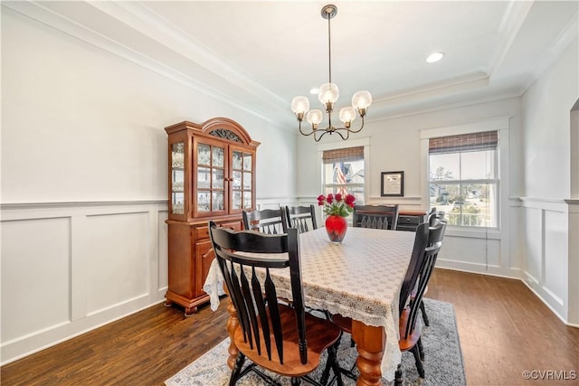 dining area featuring a tray ceiling, dark wood-style flooring, a healthy amount of sunlight, and a notable chandelier