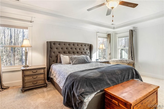 bedroom featuring light carpet, multiple windows, a raised ceiling, and baseboards