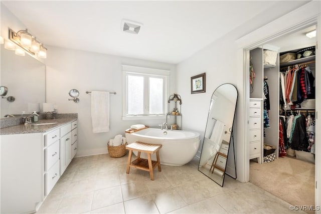 full bath with a freestanding bath, a spacious closet, visible vents, and vanity