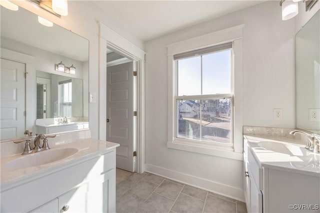 full bath featuring two vanities, a sink, and a wealth of natural light