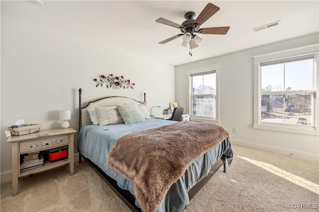 carpeted bedroom featuring a ceiling fan, visible vents, and baseboards