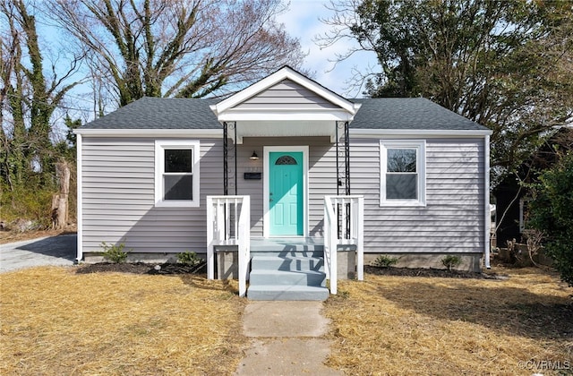 bungalow-style home with a shingled roof and a front yard