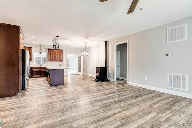 interior space with light wood-type flooring, visible vents, baseboards, and ceiling fan with notable chandelier