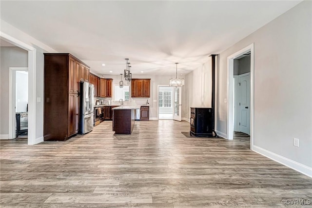 kitchen with light wood-style flooring, open floor plan, light countertops, stainless steel refrigerator with ice dispenser, and a center island