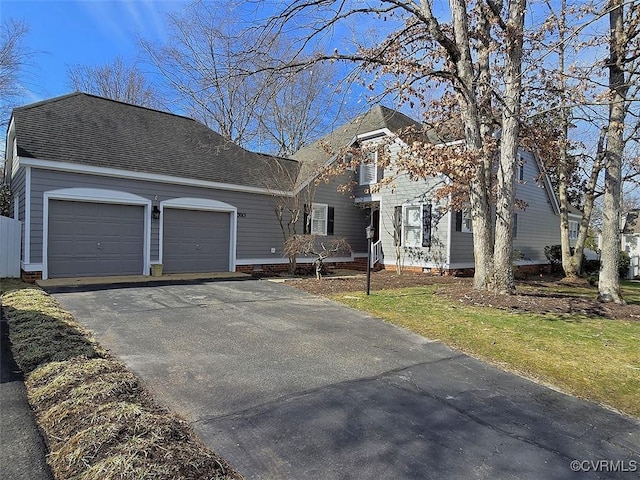 view of front facade featuring a garage, driveway, and a shingled roof