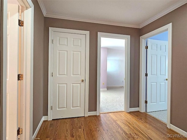 hallway with baseboards, wood finished floors, and ornamental molding