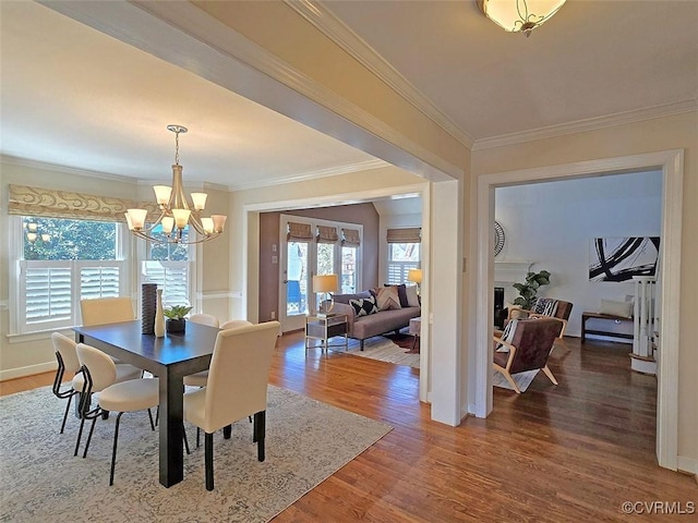 dining area with crown molding, a chandelier, wood finished floors, and a healthy amount of sunlight