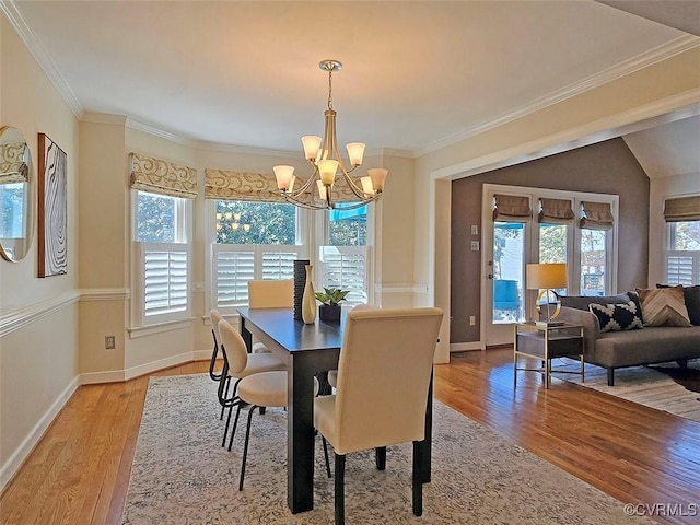 dining space with baseboards, a notable chandelier, crown molding, and light wood finished floors