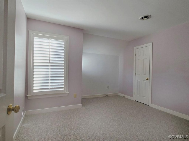 carpeted spare room with visible vents and baseboards