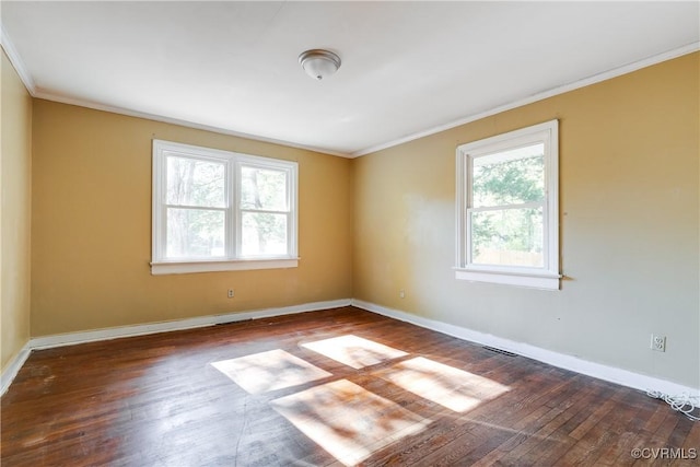 empty room with ornamental molding, hardwood / wood-style floors, visible vents, and baseboards