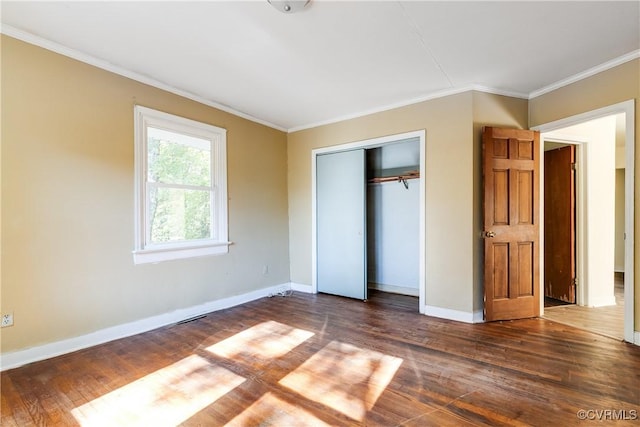 unfurnished bedroom featuring a closet, crown molding, baseboards, and wood finished floors