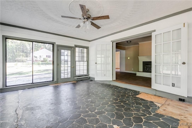 empty room with ornamental molding, stone finish flooring, a fireplace with raised hearth, and a textured ceiling