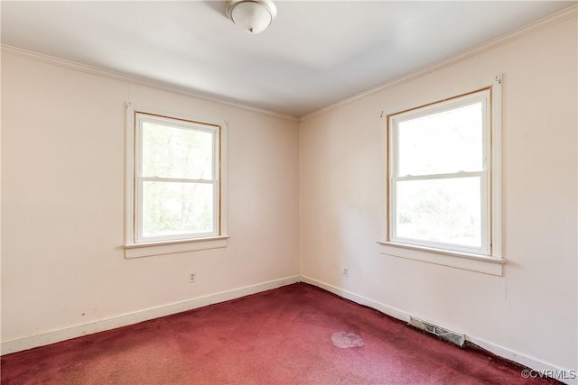 unfurnished room with crown molding, dark carpet, visible vents, and a healthy amount of sunlight