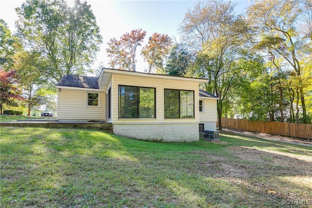 back of house with central AC unit, a lawn, and fence