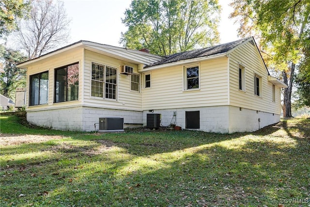 view of side of home featuring a lawn, a wall mounted air conditioner, and central air condition unit