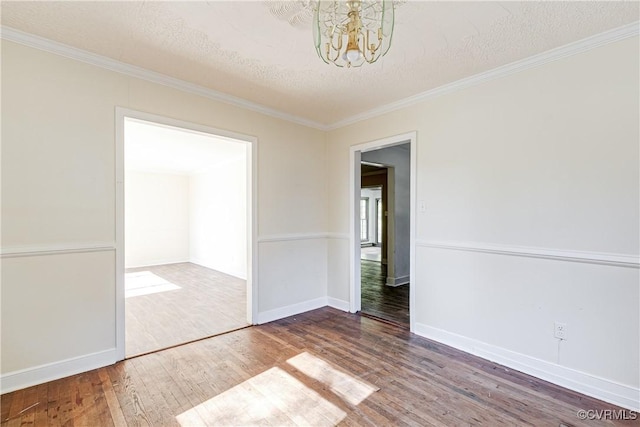 unfurnished room with crown molding, an inviting chandelier, a textured ceiling, wood finished floors, and baseboards