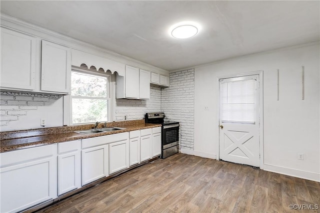 kitchen with a sink, white cabinets, light wood-style floors, stainless steel electric range, and dark countertops