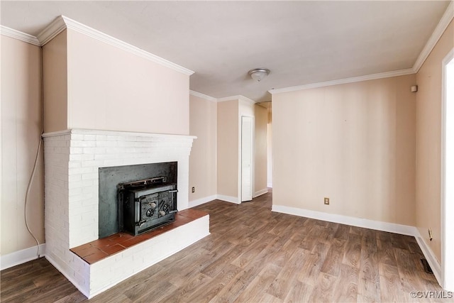 unfurnished living room featuring a wood stove, crown molding, baseboards, and wood finished floors