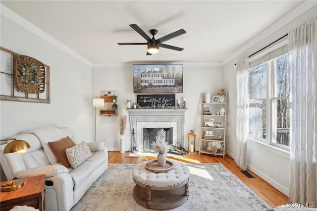 living room with a fireplace with flush hearth, crown molding, and wood finished floors