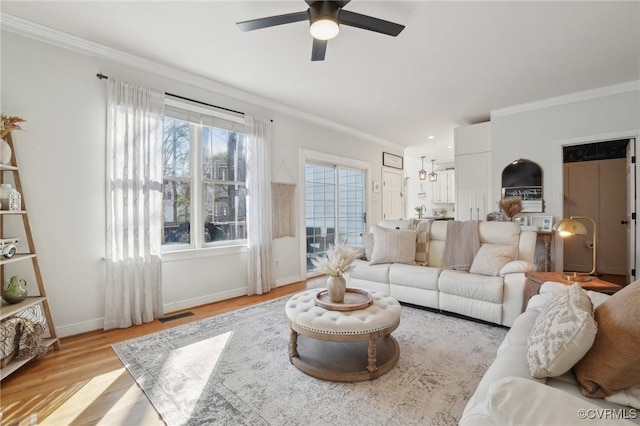 living room with crown molding, visible vents, ceiling fan, light wood-type flooring, and baseboards