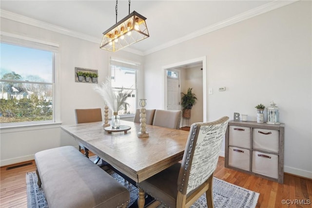 dining room with light wood-type flooring, baseboards, visible vents, and ornamental molding