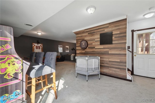 interior space featuring wood walls, baseboards, an accent wall, and visible vents