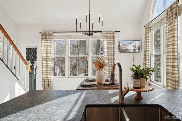 dining space featuring a towering ceiling, an inviting chandelier, and stairs