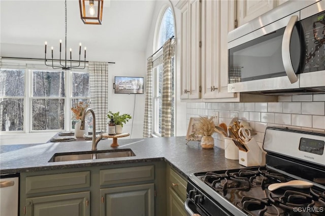 kitchen with appliances with stainless steel finishes, backsplash, a sink, and an inviting chandelier