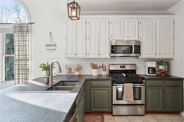 kitchen featuring appliances with stainless steel finishes, white cabinets, a sink, and tasteful backsplash