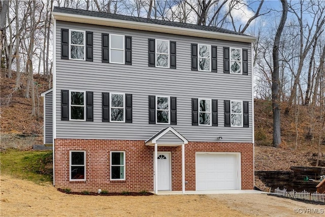 colonial house with a garage, driveway, and brick siding