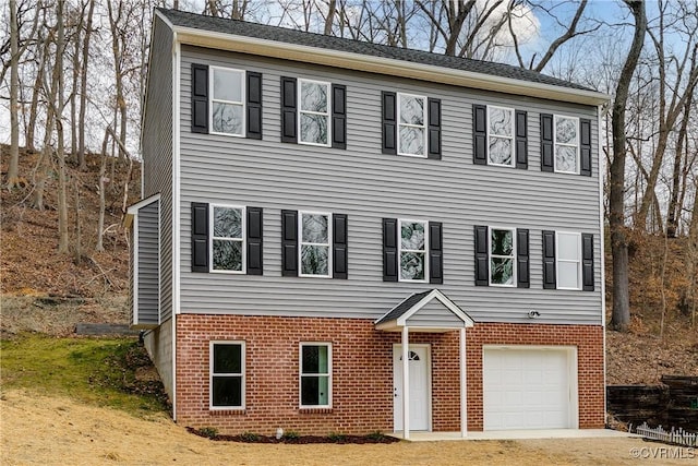 colonial inspired home featuring a garage, driveway, and brick siding