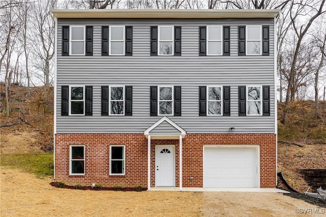 colonial home with a garage, driveway, brick siding, and a front lawn