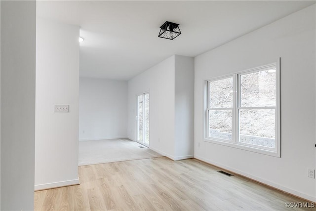 spare room featuring visible vents, baseboards, and wood finished floors