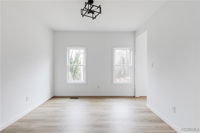 spare room with visible vents, light wood-style flooring, and baseboards