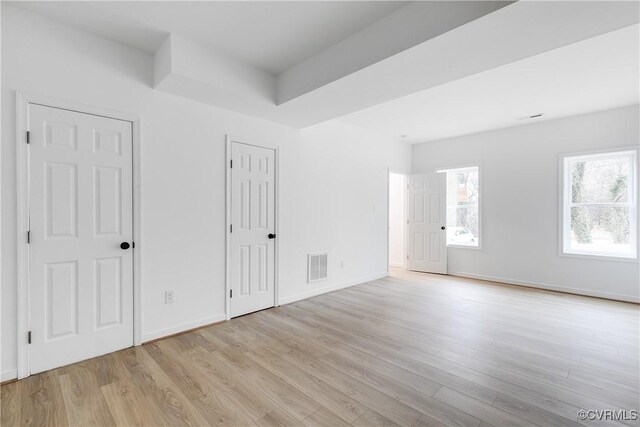 empty room featuring baseboards, visible vents, and light wood finished floors