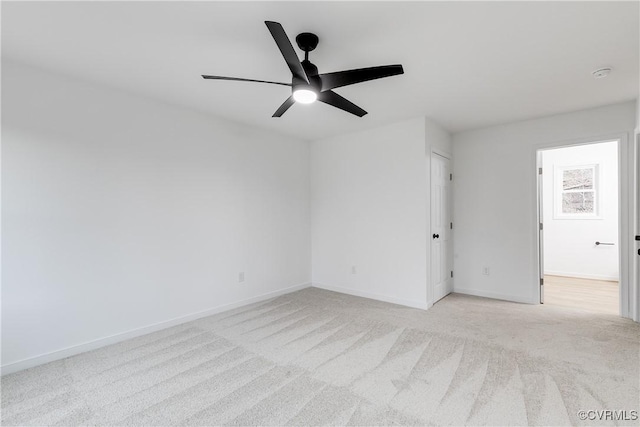 carpeted spare room with a ceiling fan and baseboards