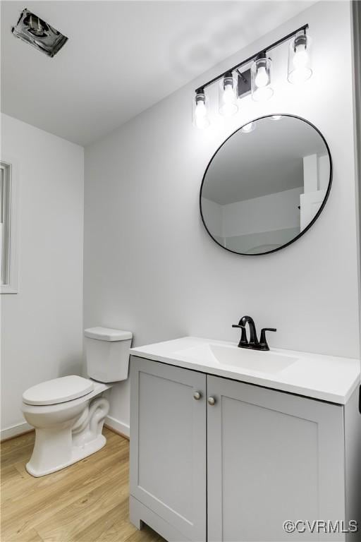 bathroom featuring baseboards, vanity, toilet, and wood finished floors