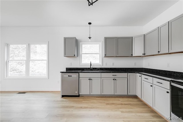 kitchen featuring dishwasher, gray cabinets, a sink, and visible vents