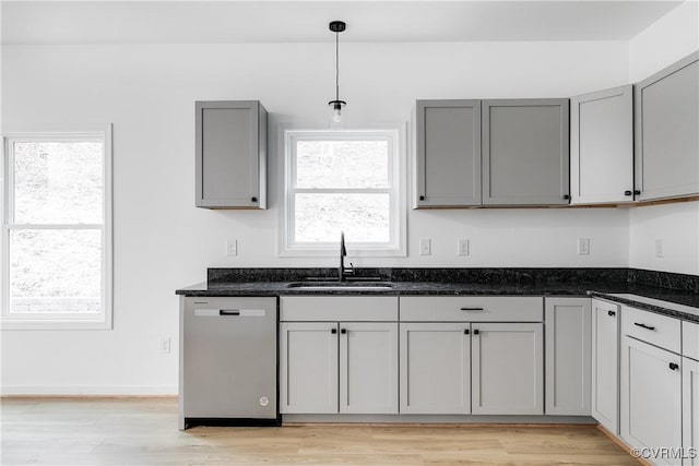 kitchen with gray cabinets, light wood-style flooring, a sink, dark stone counters, and dishwasher