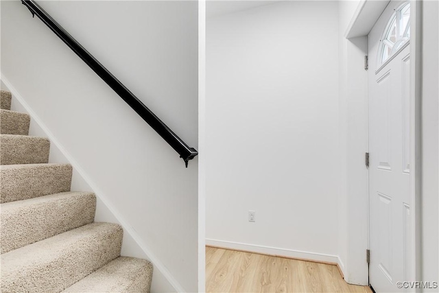 staircase featuring baseboards and wood finished floors