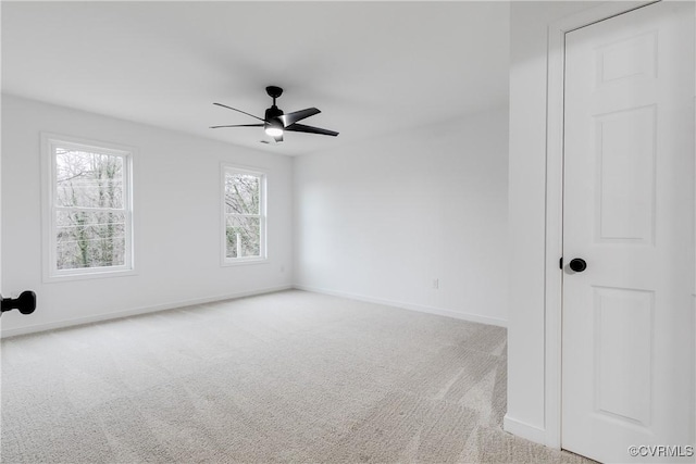 carpeted empty room featuring ceiling fan and baseboards