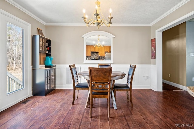 dining area with wood finished floors, a notable chandelier, a healthy amount of sunlight, and ornamental molding