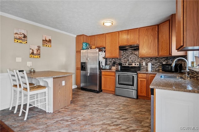 kitchen with under cabinet range hood, brown cabinets, appliances with stainless steel finishes, a peninsula, and a sink