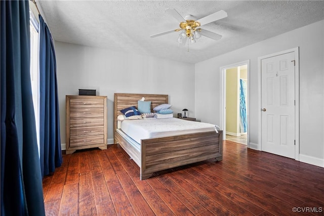 bedroom with a textured ceiling, baseboards, and dark wood-style flooring