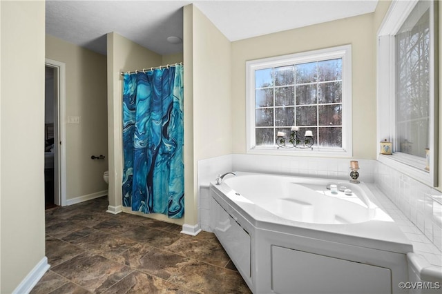 full bathroom featuring a shower with shower curtain, a garden tub, toilet, and baseboards