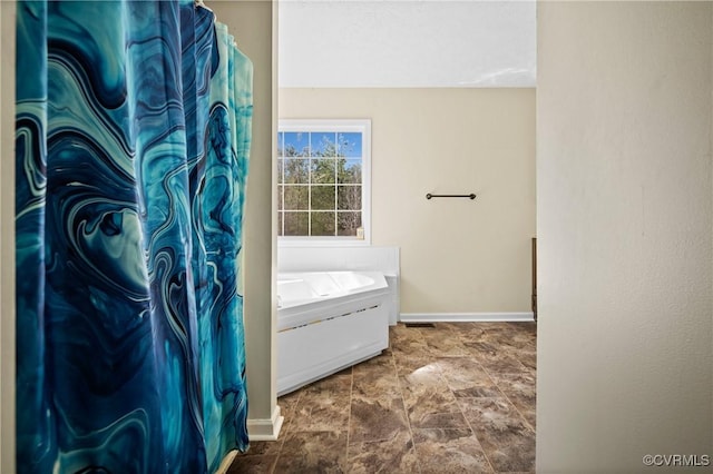 full bathroom with stone finish floor and baseboards