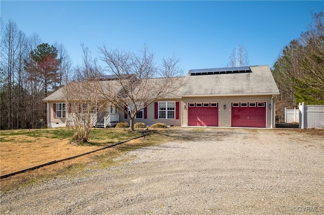 view of front facade featuring solar panels, fence, dirt driveway, crawl space, and an attached garage