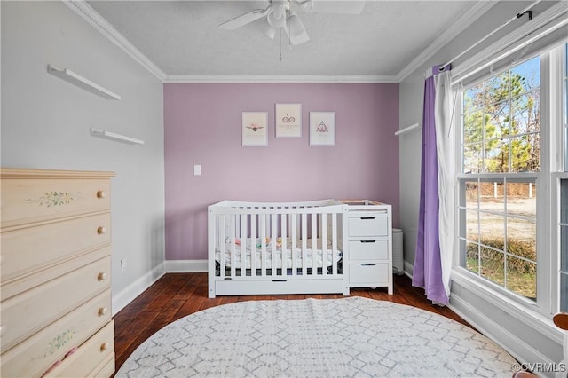 bedroom with baseboards, ceiling fan, ornamental molding, hardwood / wood-style flooring, and a nursery area