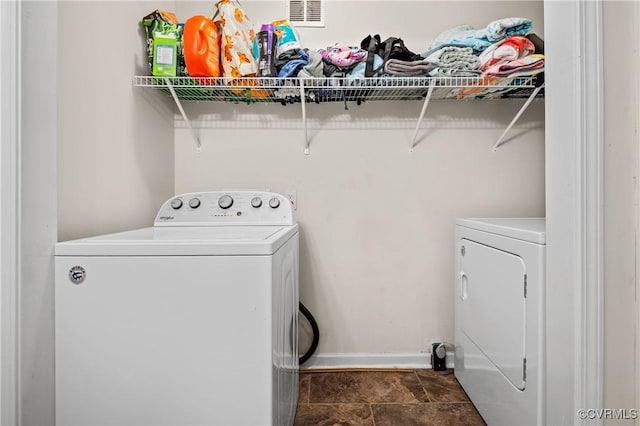 clothes washing area with visible vents, stone finish flooring, separate washer and dryer, baseboards, and laundry area