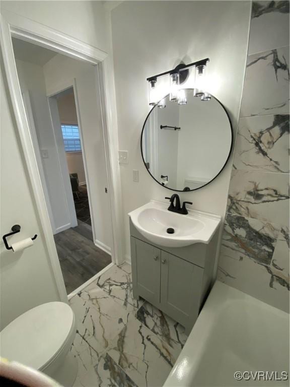 bathroom with toilet, marble finish floor, and vanity